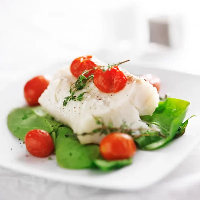 Cooked halibut on spinach with cherry tomatoes